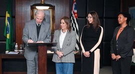 O presidente do TRE-SP, des. Encinas Manfré, assina documento sobre um púlpito de madeira, enqua...