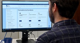 Pessoa olha para tela de computador em que aparece o formulário da Ouvidoria do TRE-SP