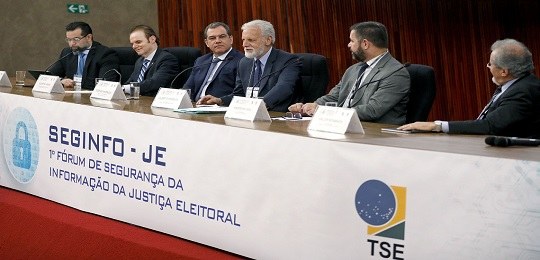 1° Fórum de Segurança da Informação da Justiça Eleitoral debate proteção de dados Fotografia de uma bancada onde se lê “SEGINFO-JE: 1º Fórum de Segurança da Informação da Justiça...