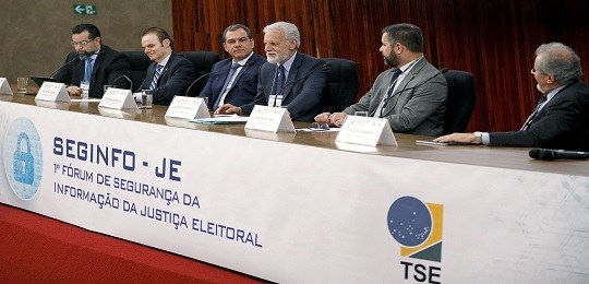 Fotografia de uma bancada onde se lê “SEGINFO-JE: 1º Fórum de Segurança da Informação da Justiça...