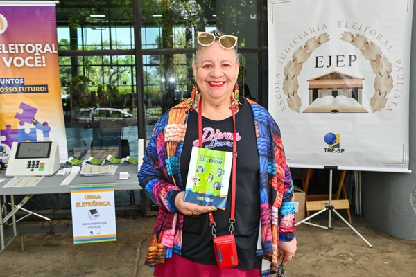 Célia Freitas sostiene el Manual del Elector en una actividad del TRE-SP