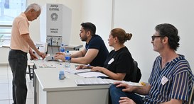 Um homem idoso de cabelos brancos sendo identificado por meio da biometria em uma seção eleitoral