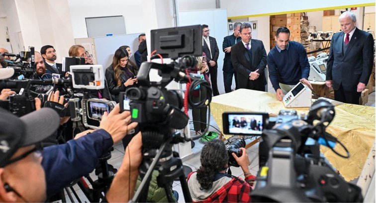 Várias câmeras e jornalistas gravam e assistem a cerimônia de carga e lacração das urnas eletrôn...