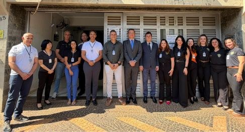 Equipe da Corregedoria e servidoras e servidores de pé diante da sede de cartório eleitoral na r...
