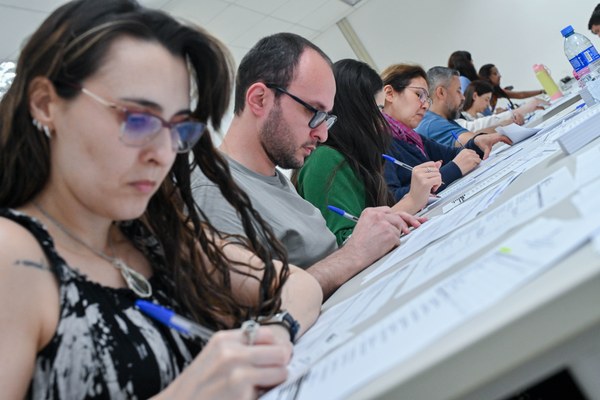 Servidores e autoridades de órgãos externos, além de representantes de partidos políticos, preenchem cédulas manualmente