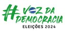 Logotipo com texto em verde #VozDaDemocracia, no qual a letra O representa de forma estilizada o...