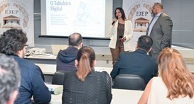 Fotografia em ambiente fechado de uma palestra promovida pela Ejep. Uma mulher fala ao microfone...