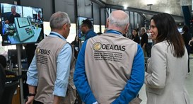 Três observadores internacionais da OEA, vestindo coletes beges identificados com o logotipo da ...