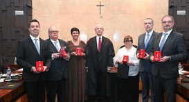 Ladeando a autoridade central, encontram-se cinco homens e duas mulheres em trajes de passeio co...