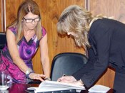 Diretora-Geral, Jade Almeida Prometti, colhe assinatura da juíza Claudia Fanucchi no Livro de Posse