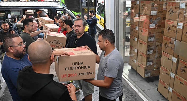 Pessoas formam um cordão humano para transportar caixas de urnas na 1ª Zona Eleitoral até uma va...